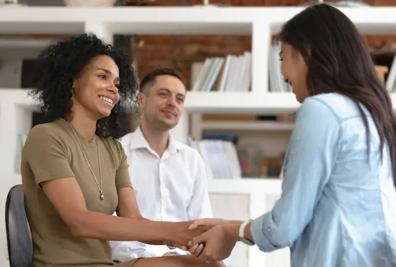 Three people sitting and shaking hands.