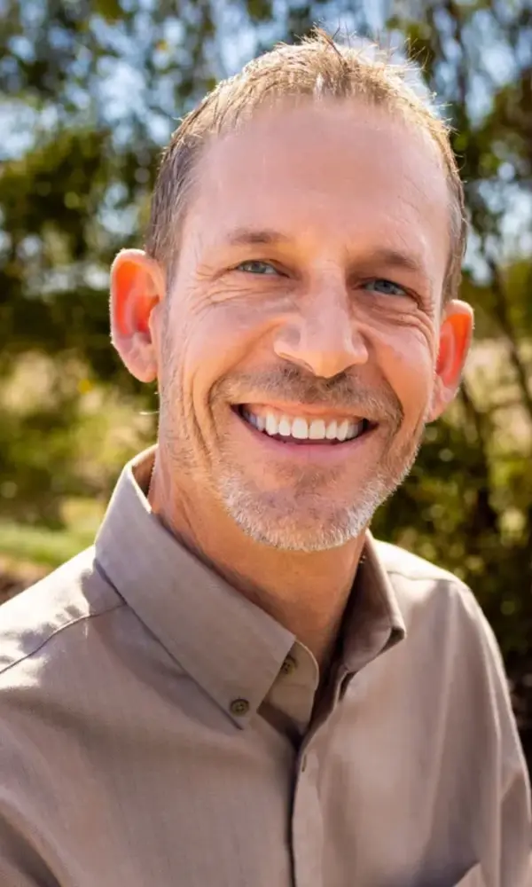 1734893593_9 Smiling man outdoors in natural setting.