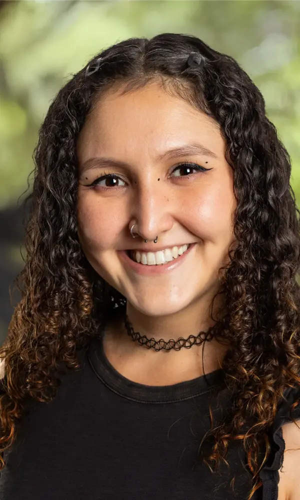 1743792865_webaraceli Smiling woman with curly hair, blurred background.