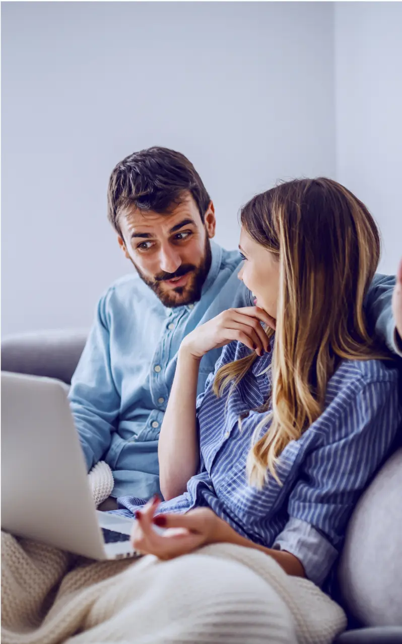 Couple sitting on sofa with laptop.