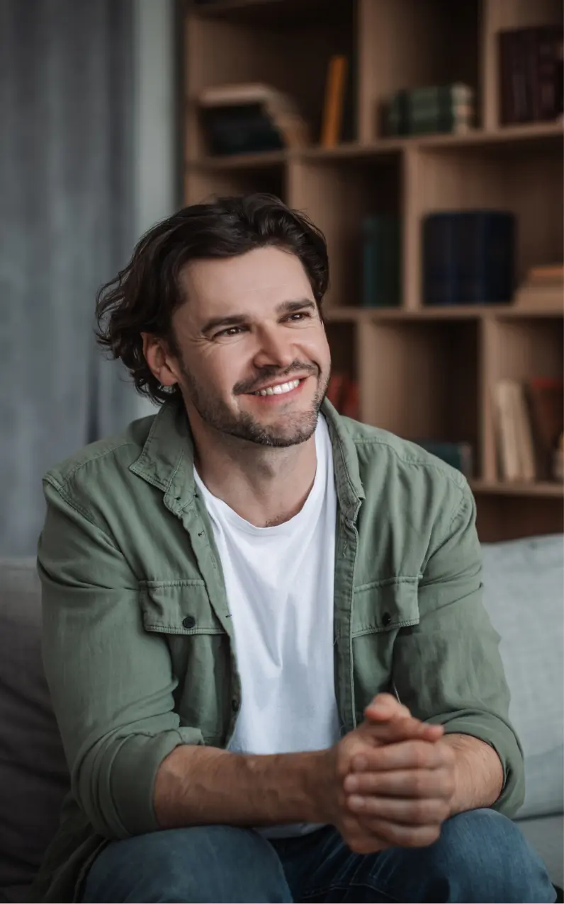 Smiling man sitting on a couch indoors.