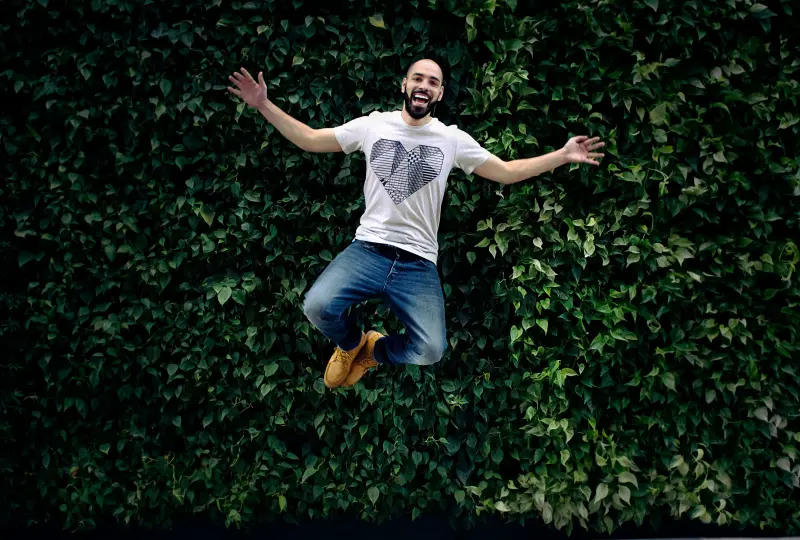 g 03 Man joyfully jumping in front of greenery.