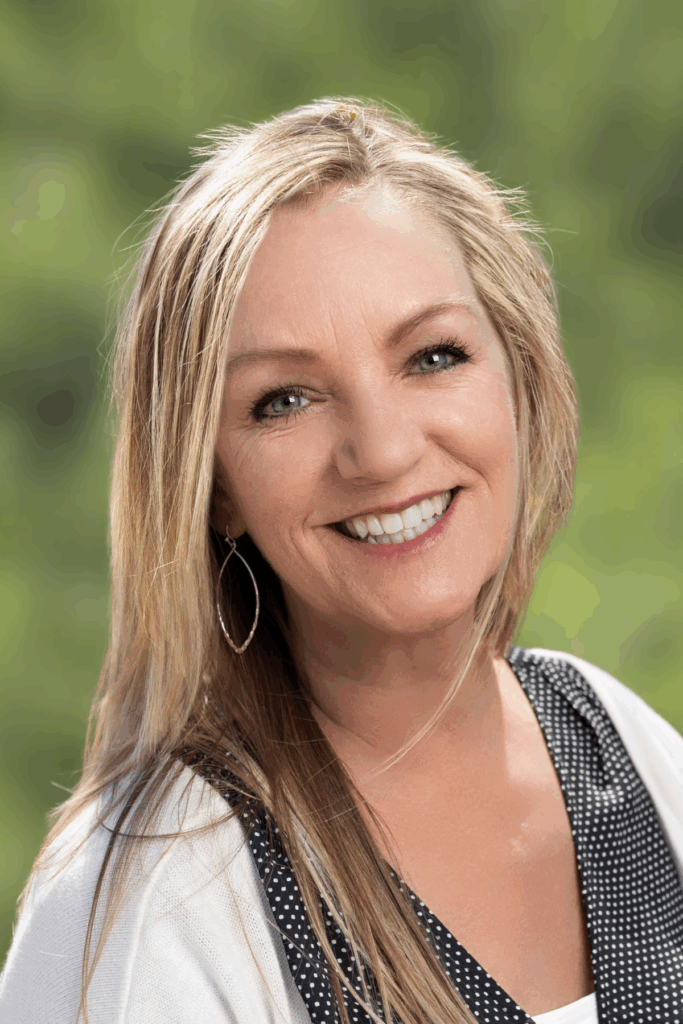 Smiling woman with long blonde hair outdoors.