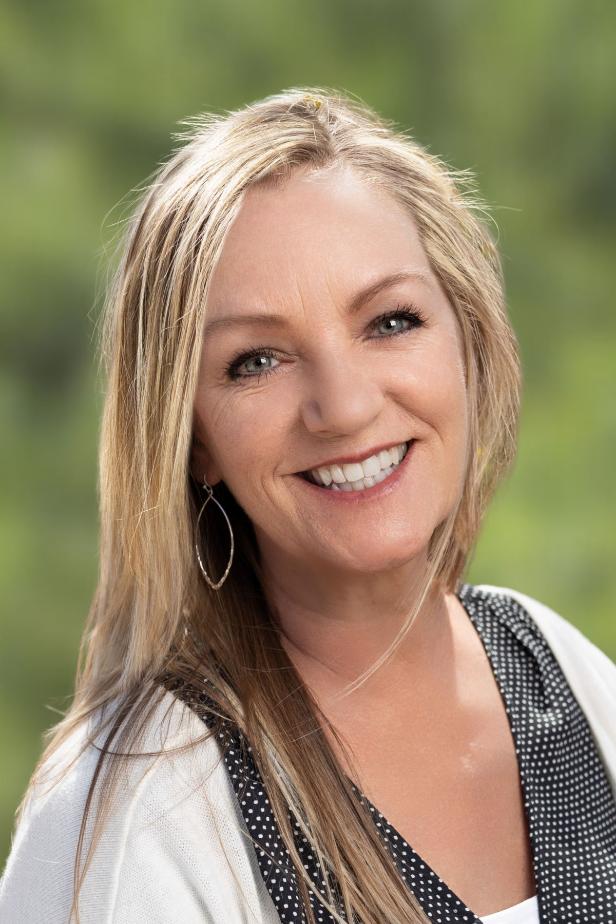 Smiling woman with long blonde hair outdoors.