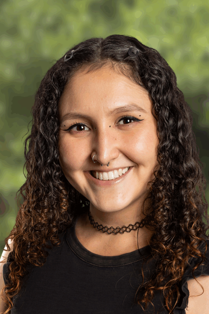 Smiling young woman with curly hair outdoors.