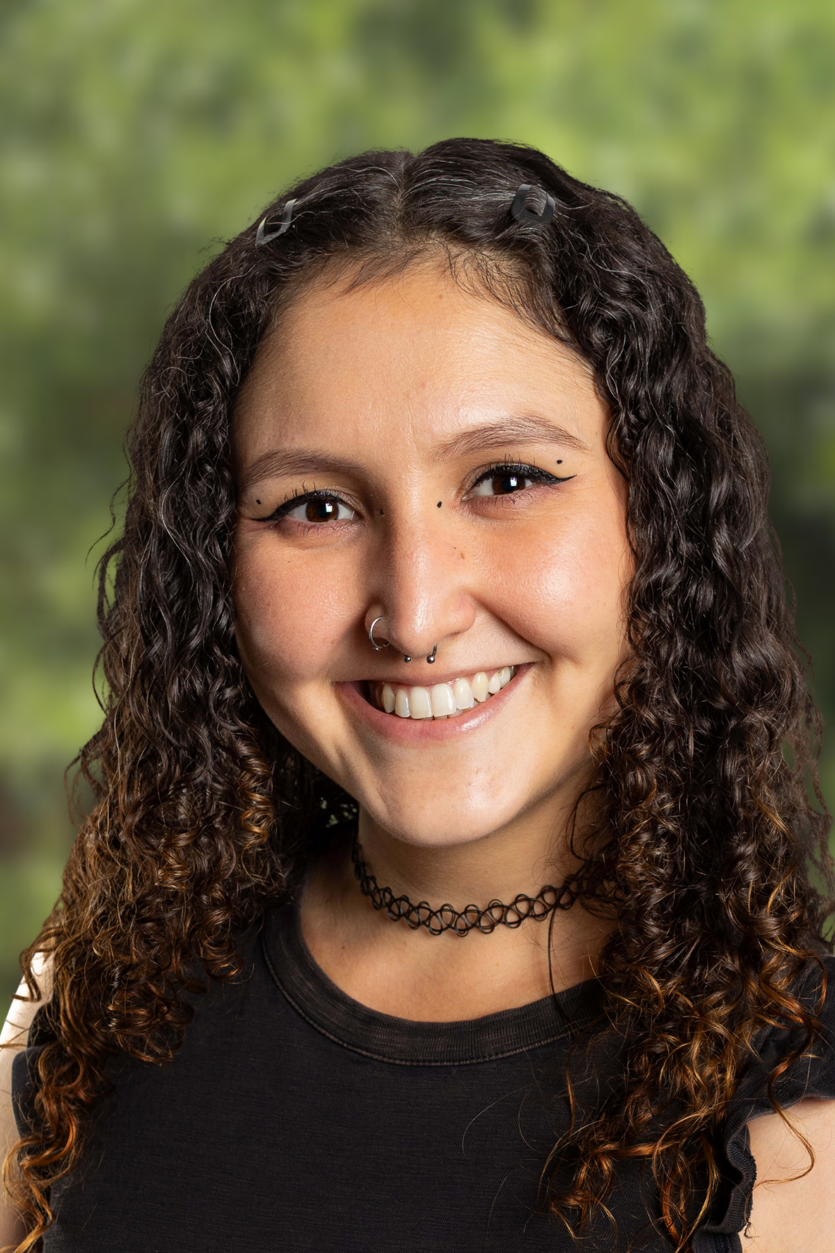 Smiling young woman with curly hair outdoors.